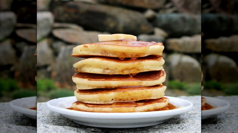 Stack of pancakes with butter and syrup on white plate at Polly's Pancake Parlor