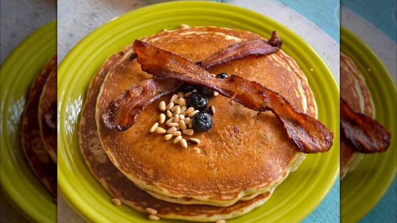 Bacon on top of pancakes on green plate