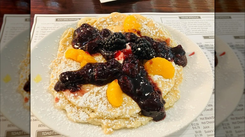 Stack of blackberry peach pancakes on white plate