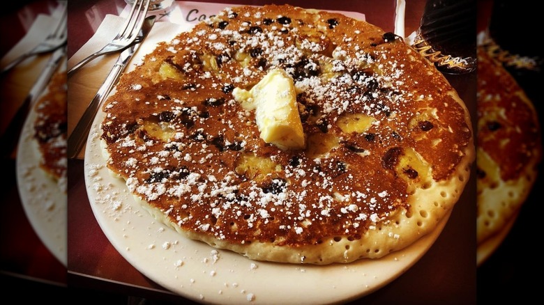 Large chocolate chip banana pancake on white plate