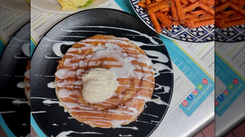 Top-down view of pancakes with glaze and butter on black plate
