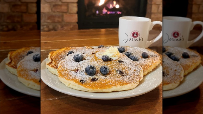 Blueberry pancakes on white plate in front of white Josiah's mug