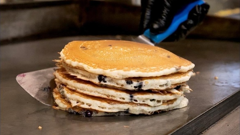 Stack of blueberry pancakes on griddle top