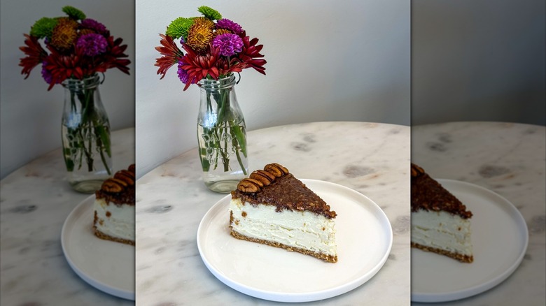 Pecan cheesecake on plate, vase of flowers behind