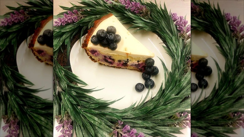 Slice of cheesecake with blueberries on top on plate surrounded by wreath