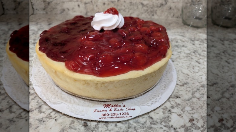 Cheesecake covered with red berries on marble countertop