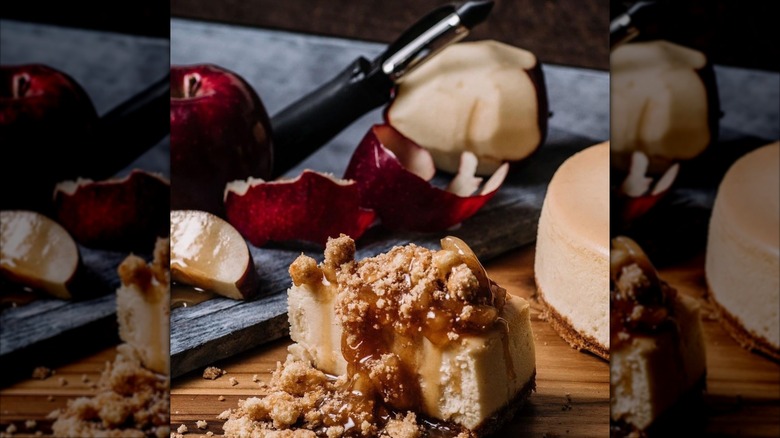 Apple crumble cheesecake on wooden counter, apples behind