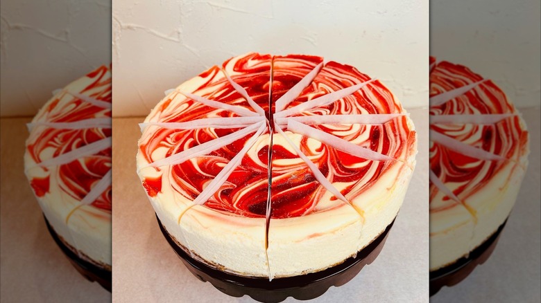 Raspberry Swirl cheesecake cut into slices, papers between slices