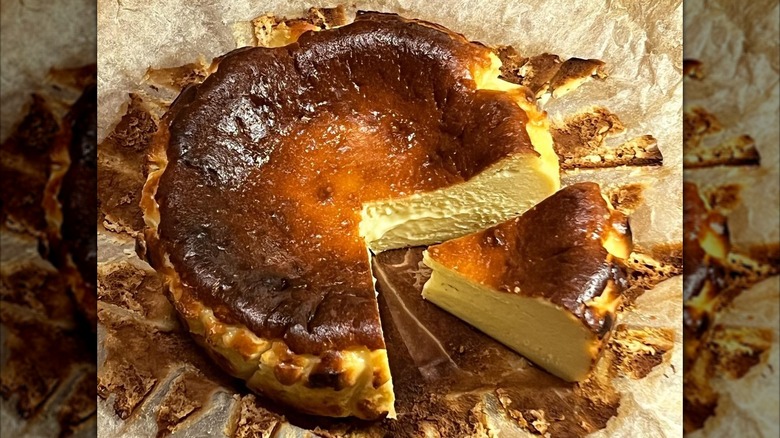 Basque burnt cheesecake with slice cut out on parchment paper