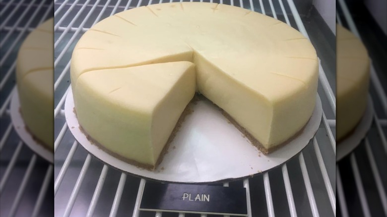 Plain cheesecake with slice cut out in display case