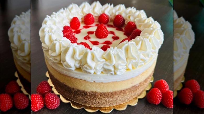 Whole raspberry cheesecake with whipped cream and raspberries
