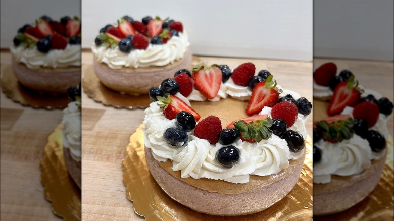 Two mixed berry cheesecakes topped with fruit and whipped cream