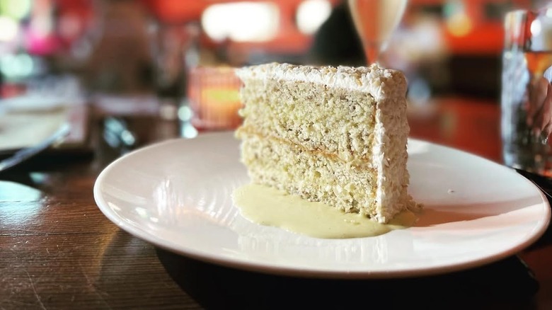 Slice of coconut cake on plate with sauce