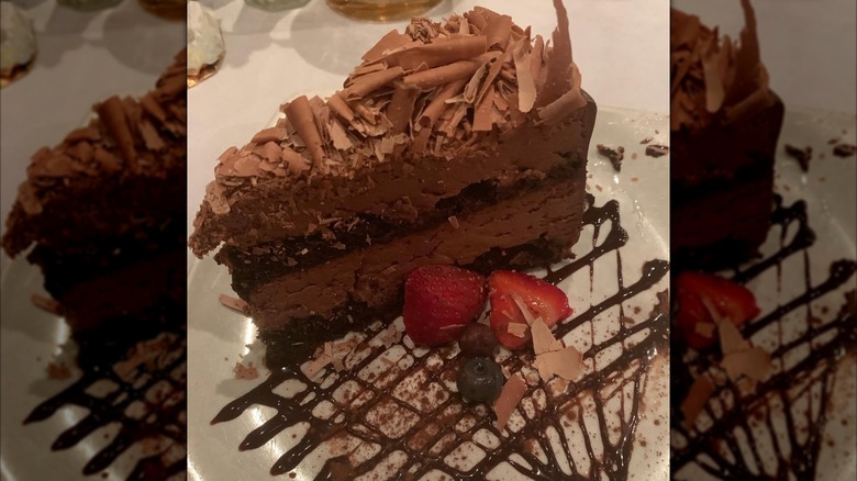 Slice of double chocolate mousse cake with berries and chocolate sauce
