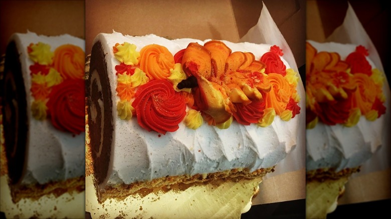 Pumpkin roll with autumn-themed frosting in pastry box