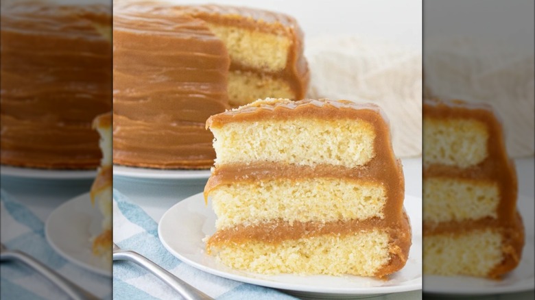 Slice of caramel layer cake on plate with whole cake in background