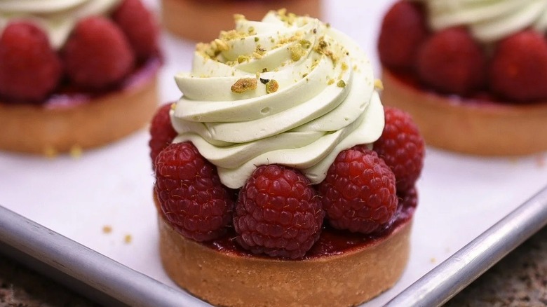 Pistachio cake topped with raspberries and Chantilly cream