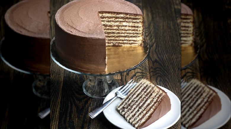 Slice of classic Smith Island cake on plate with whole cake on serving platter