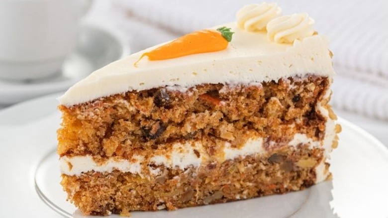 Slice of carrot cake on plate with carrot piped on top