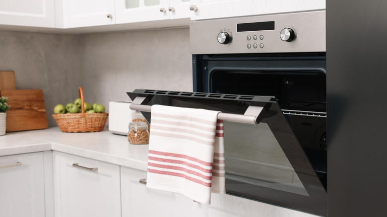 Open oven door with a striped kitchen towel hanging from the handle