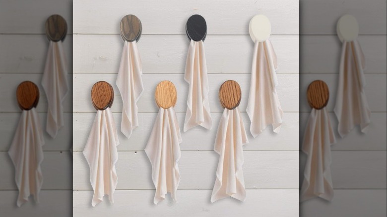 A collection of different hues of Amish wooden marble towel holders on a white wall