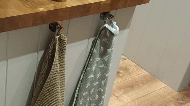 A towel bar that is attached beneath the counter space with white towels hanging from it