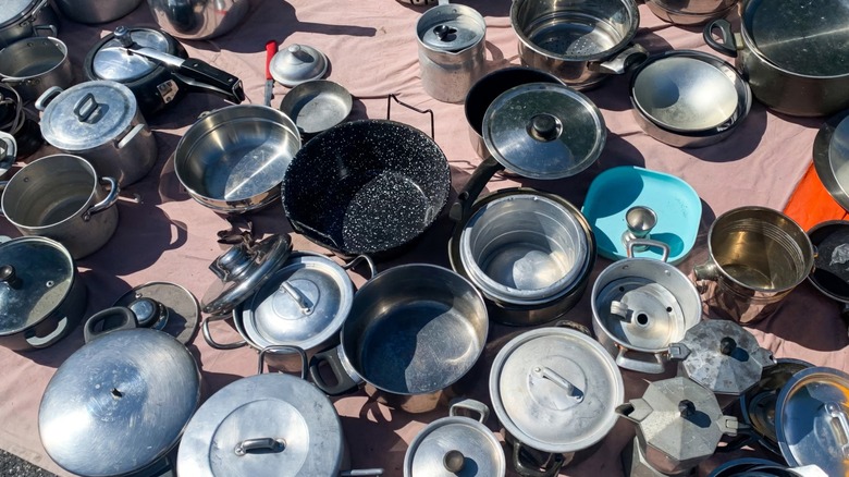 Dozens of pots and pans sitting on the ground