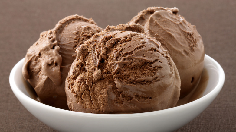 Three scoops of chocolate ice cream in a white bowl