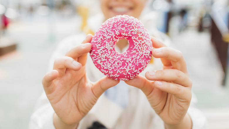 Person holding a pink sprinkled donut