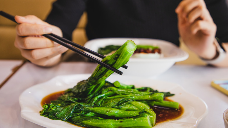 Person enjoying Cantonese steamed vegetables.