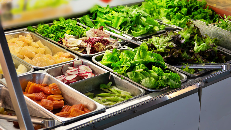 Salad bar with various vegetables, such s lettuce, carrots and radishes.
