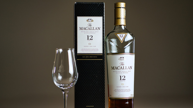 A half-full bottle of Macallan Sherry Oak 12 Years Old whisky next to the box and a glass