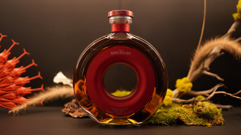 The round Macallan Time : Space Mastery whisky bottle on a display table with artefacts from nature