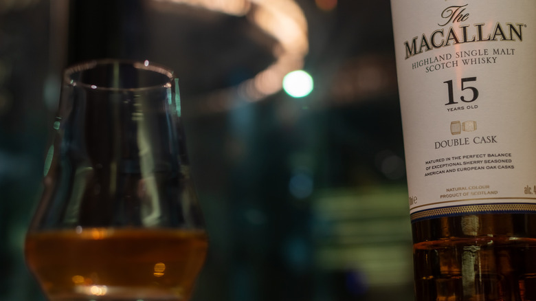 A close-up of a portion of Macallan Double Cask 15 Years Old whisky in a glass next to the bottle