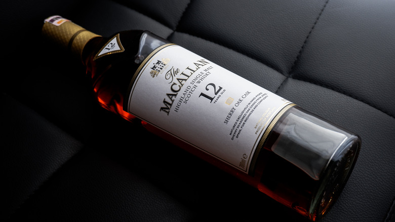 A close up on the Macallan Sherry Oak 12 whisky bottle diagonally laid on a stitched leather surface