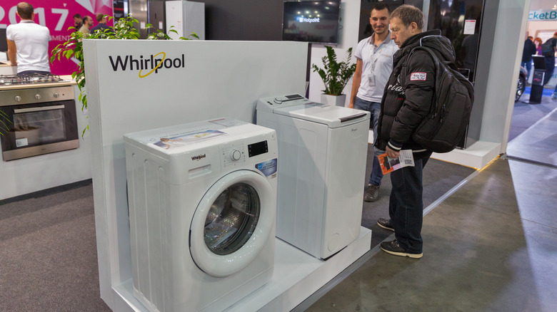 Whirlpool appliances in a store showroom with customers and sales staff