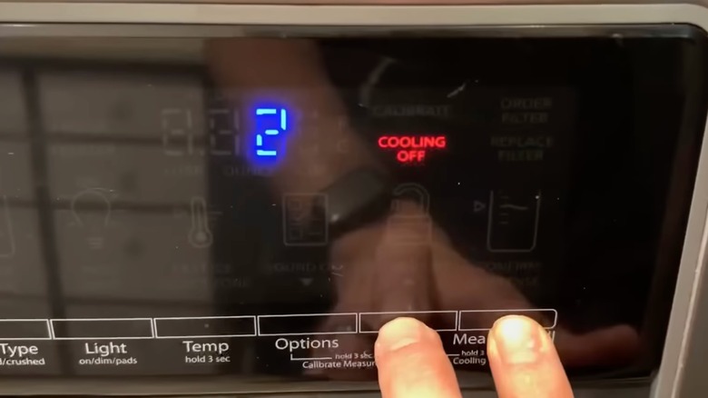 A hand presses lock and measured fill buttons with cooling off display and countdown on unit