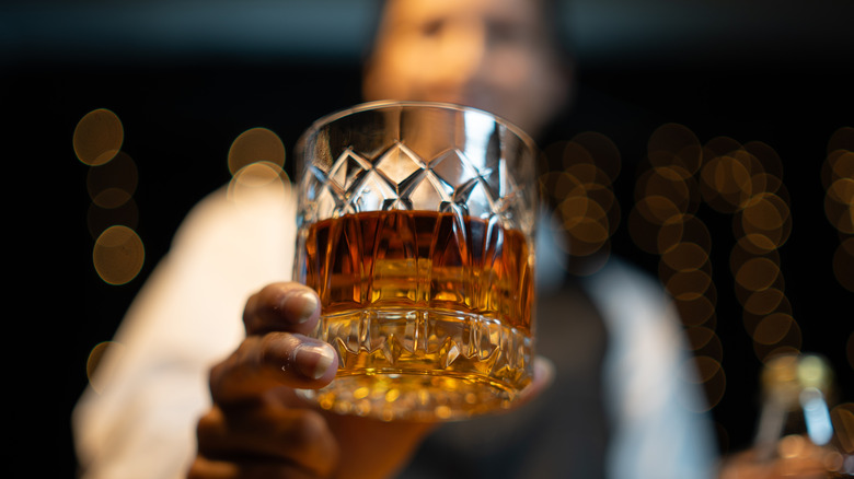 bartender holding glass of whisky