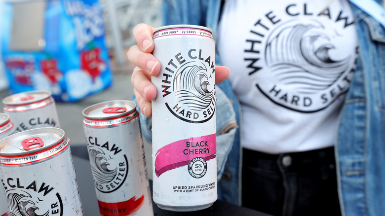 Person in white claw shirt with other cans