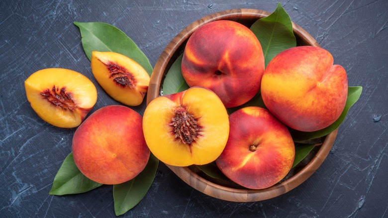 Bowl of whole and sliced peaches from above