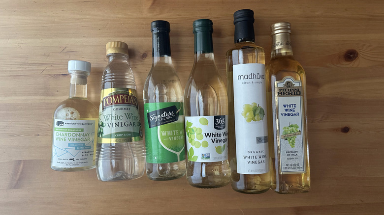 Six bottles of white wine vinegar on wooden table
