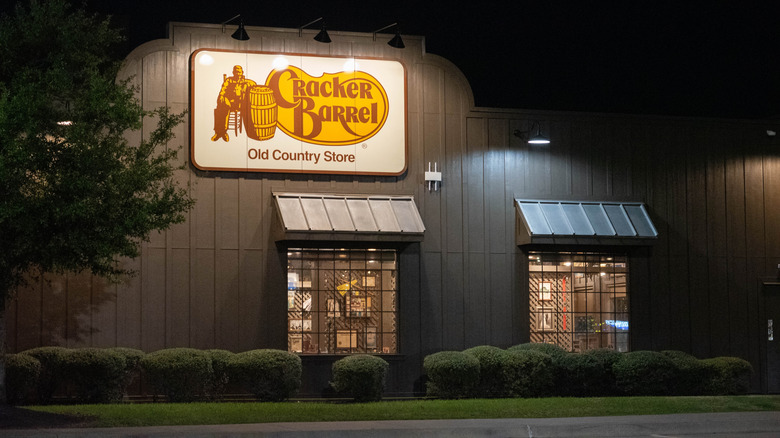 A Cracker Barrel restaurant at night with a sign illuminated by lights