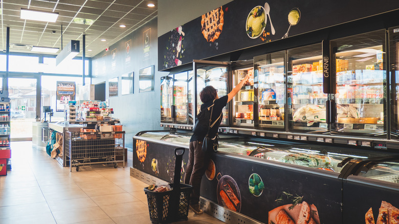 Shopper reaching for ice cream in the freezer at Aldi
