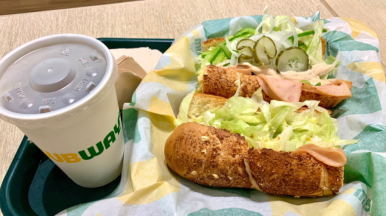 Two Subway sandwiches and a branded drink on a tray
