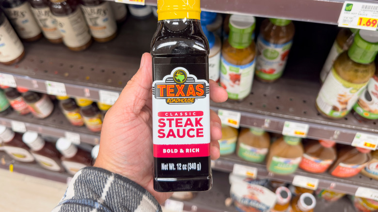 A hand holding a bottle of Texas Roadhouse steak sauce