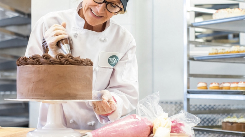 Whole Foods baker putting icing on cake