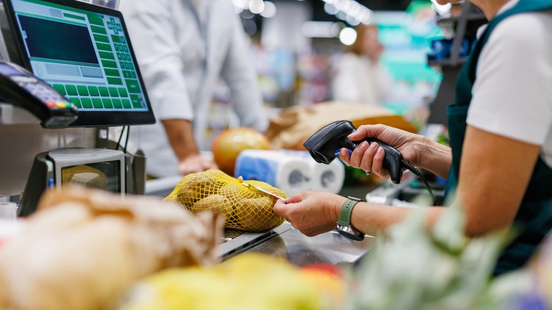 A supermarket cashier scanning a bag of lemons