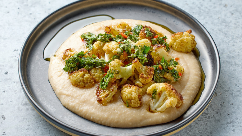 Overhead view of roasted cauliflower served atop bed of hummus