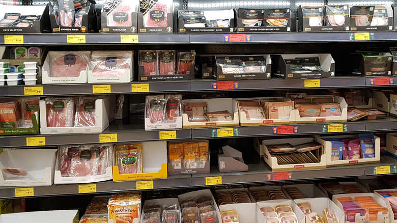 Deli section inside Aldi store displaying various cured and sliced meats on black shelves