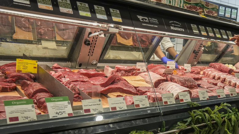 shopper talks to a butcher at grocery meat counter